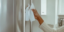 Woman Cleans Refrigerator Handle Using Disinfectant Wipe