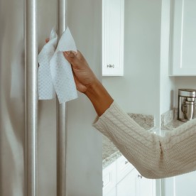 Woman Cleans Refrigerator Handle Using Disinfectant Wipe